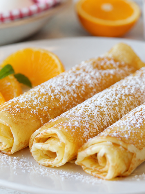 French crepe recipe served rolled with powdered sugar and orange