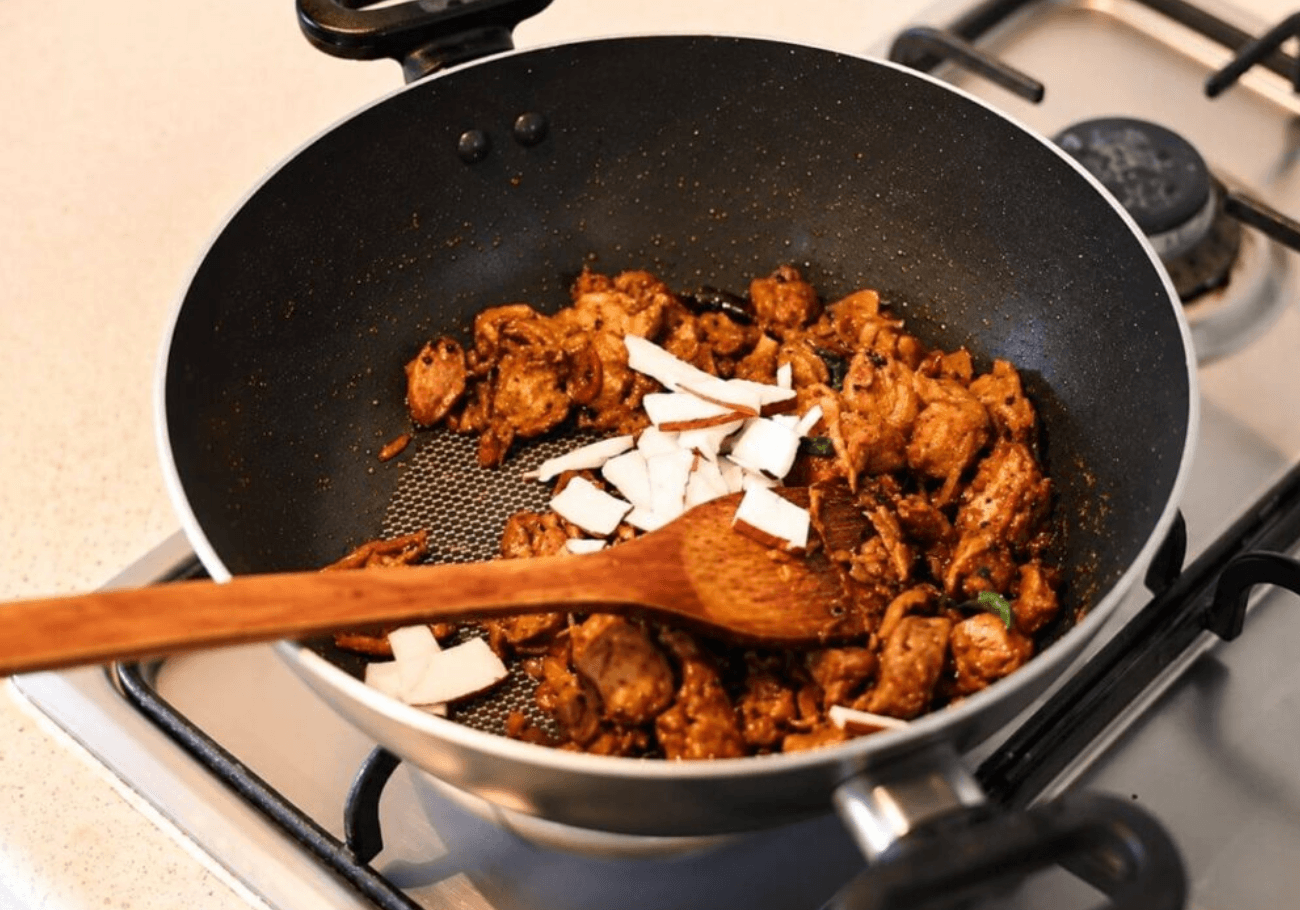 Fresh coconut added to Kerala chicken gizzard thoran in pan