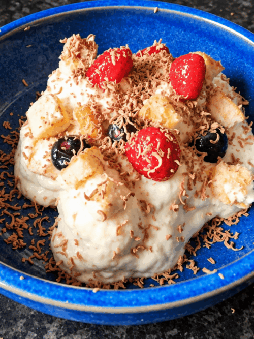 Creamy banana pudding recipe with berries, Swiss roll and grated chocolate