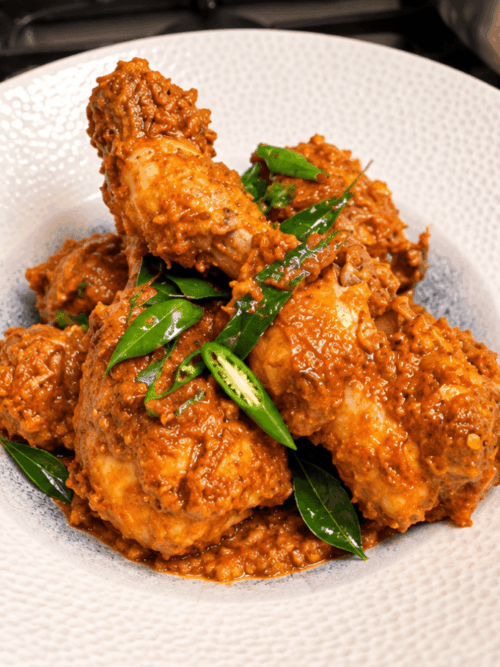 Chicken drumstick coconut masala garnished with curry leaves and green chilli