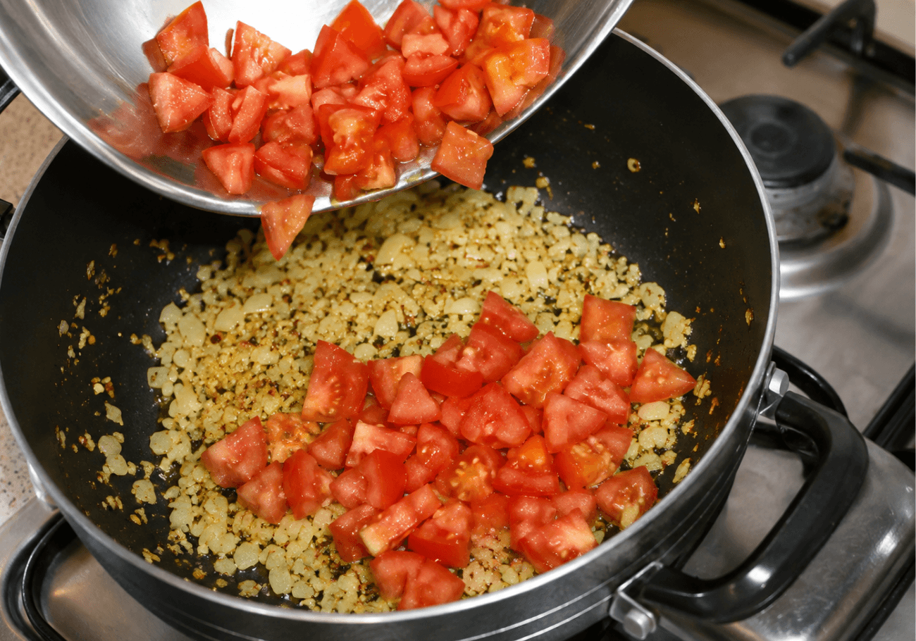 Adding chopped tomatoes to crab pasta recipe sauce