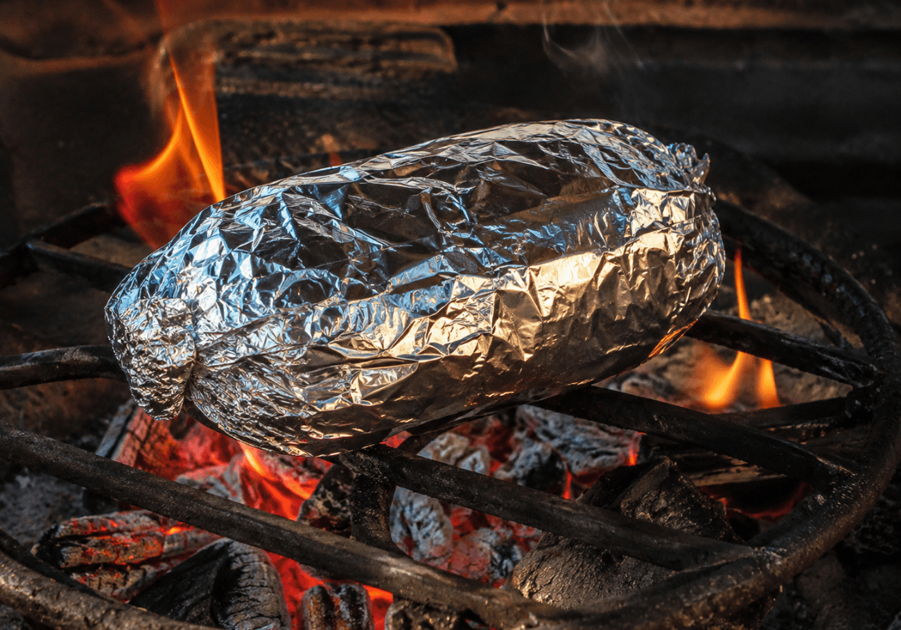 Foil wrapped tomatoes roasting over fire for roasted tomato chutne