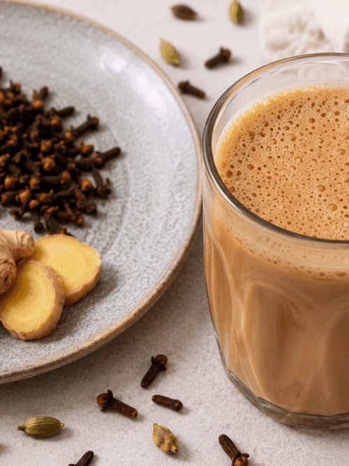 Masala chai recipe served in a glass with ginger, cardamom and cloves