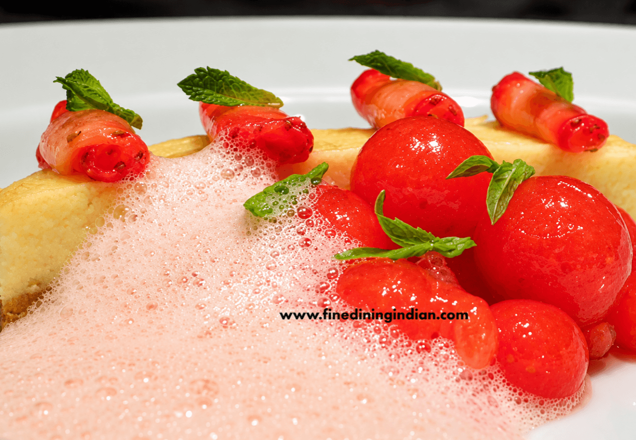 Strawberry molecular gastronomy dessert featuring red fruit spheres, strawberry foam and fresh strawberries with mint garnish.