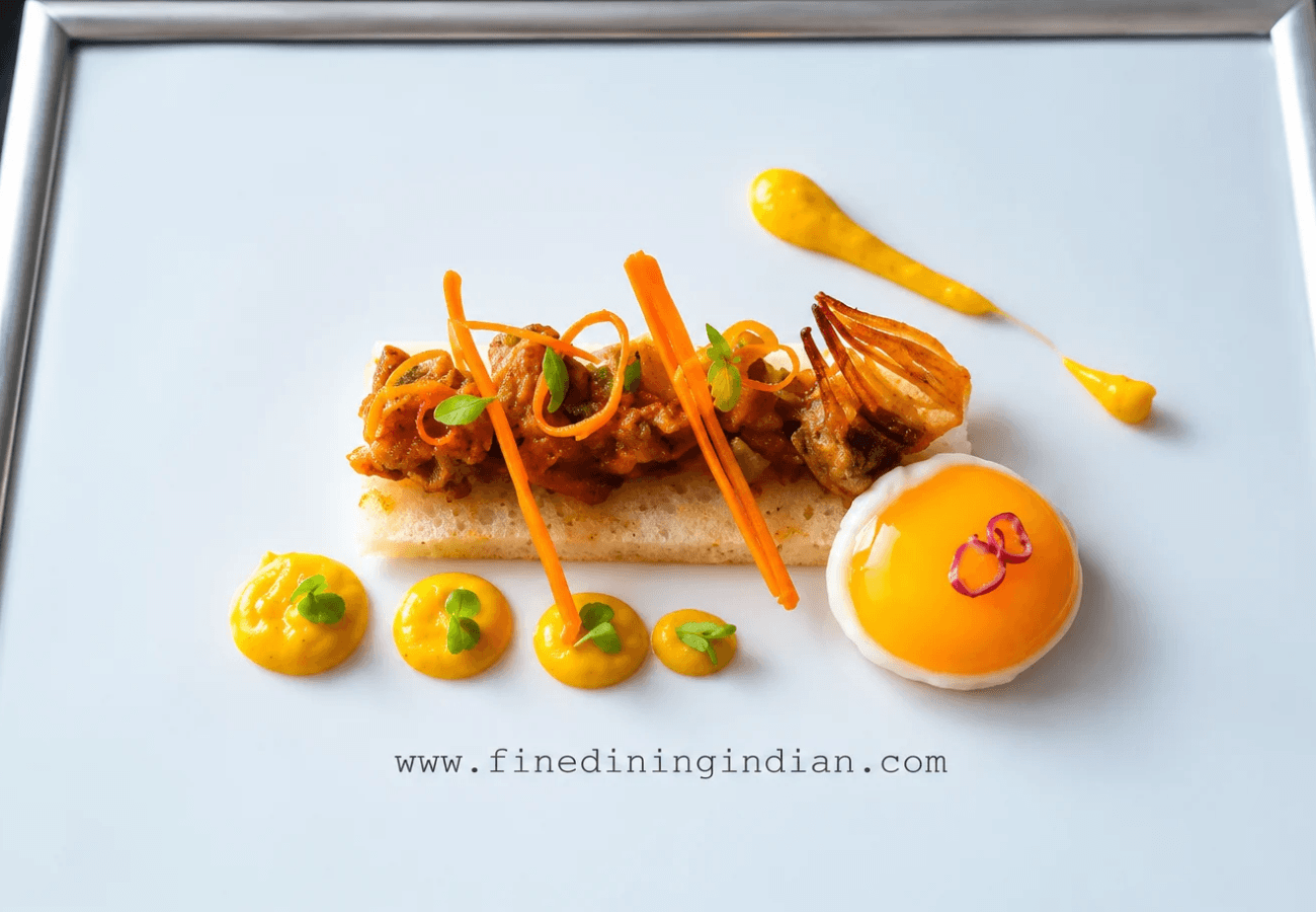 Modern Indian food presentation featuring appam, slow-braised lamb curry, fried egg, carrot purée and vegetable garnishes arranged within a photo frame.